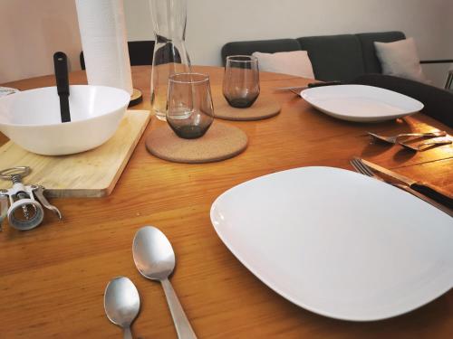 une table en bois avec des assiettes et des cuillères blanches dans l'établissement Appartement Paris 16 proche à 20 minutes de la Tour Eiffel, à Paris