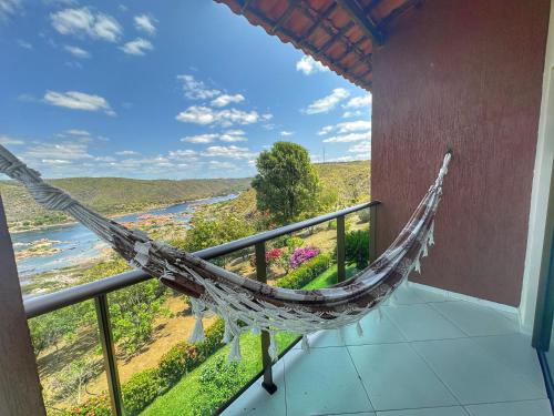 a hammock on a balcony with a view of a river at Hotel Aconchego do Velho Chico in Piranhas