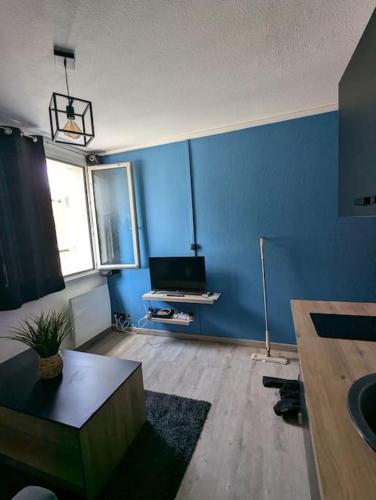 Il comprend un salon doté de murs bleus et d'une télévision. dans l'établissement Studio-centre-ville, à Saint-Nazaire