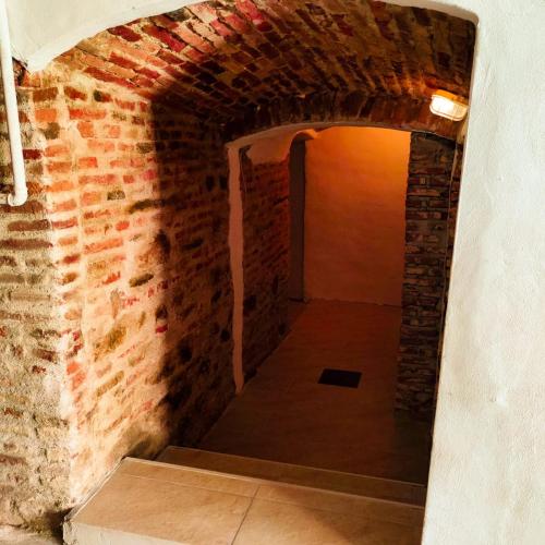 a hallway in a brick wall with an open doorway at Heltau Apartments in Cisnădie