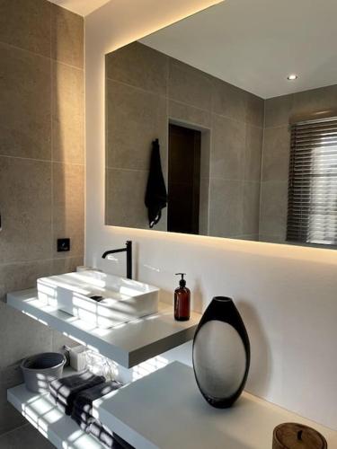 La salle de bains est pourvue d'un miroir et d'un lavabo blanc. dans l'établissement Villa Lety, à Saint-Tropez