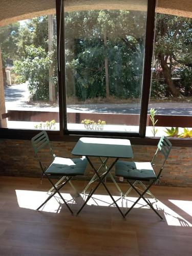 deux chaises et un bureau devant une fenêtre dans l'établissement Studio climatisé, une place de parking à la Faviére, à Bormes-les-Mimosas
