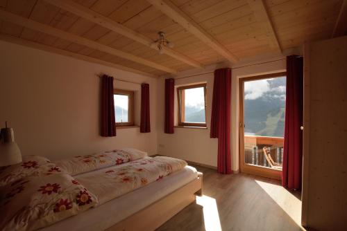een slaapkamer met een bed en 2 ramen bij Pircherhof in San Candido