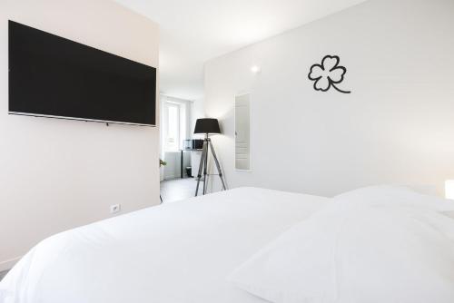 a white bedroom with a bed with a flat screen tv at Le Trèfle à Quatre Feuilles in Siorac-en-Périgord
