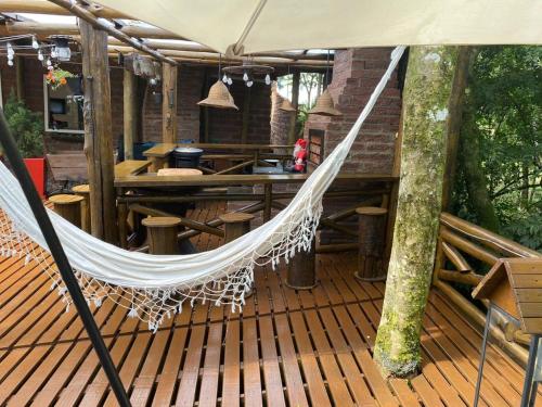 a hammock on a wooden deck with a table and a table at Chale Sobre Rodas Spa Exclusive - Localizado Próximo do Centro in Canela