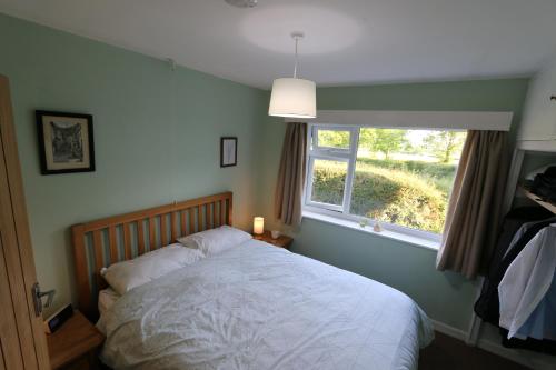 a bedroom with a bed and a window at Woodlands A Tranquil Retreat in Exbourne