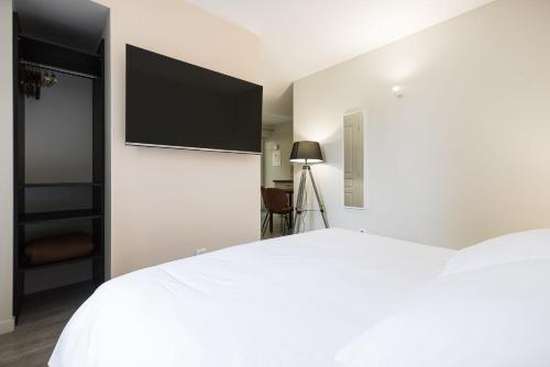 a bedroom with a white bed with a flat screen tv at Le Trèfle à Quatre Feuilles in Siorac-en-Périgord