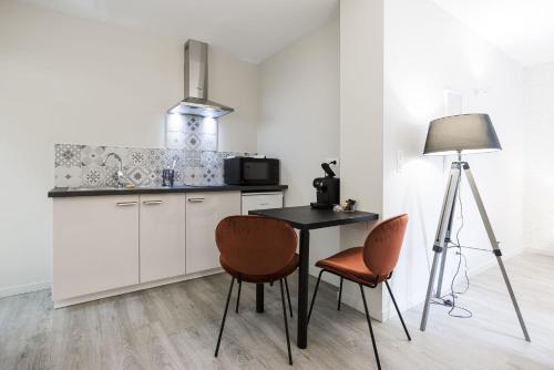 a kitchen with a table and two chairs and a lamp at Le Trèfle à Quatre Feuilles in Siorac-en-Périgord