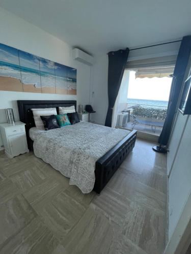 une chambre avec un grand lit et une grande fenêtre dans l'établissement Luxueux appartement front de mer, à Cannes