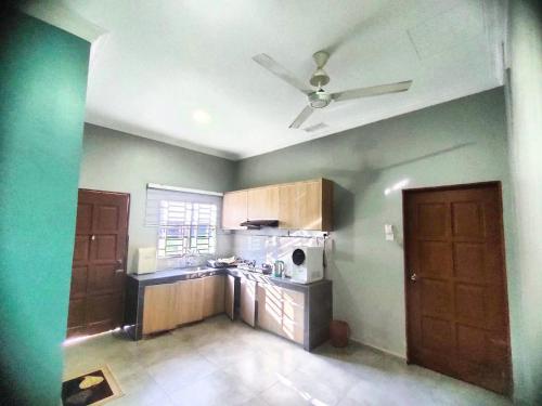 a kitchen with green walls and a ceiling fan at homestay juara meru setia alam klang in Kapar