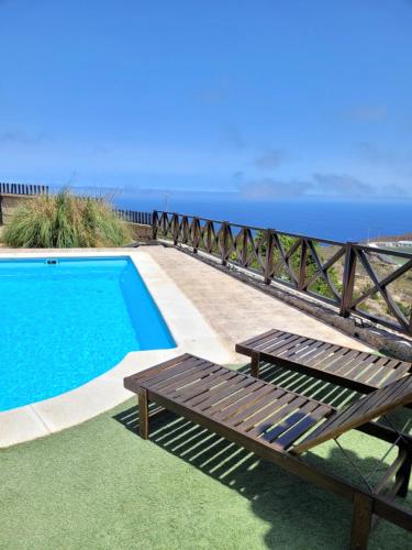 a swimming pool with a bench next to the ocean at Casa Rural Achacay in Fasnia