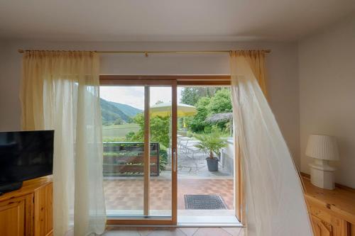 a living room with a sliding glass door to a patio at Residence Obermoarhof - Family Apartments with Pool & Playground in Vandoies
