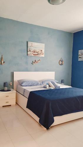 a bedroom with a bed and a blue wall at LA TERRAZZA SUL MARE camera fronte mare&vicino aereoporto SICILIAN VINTAGE STYLE SEASIDE ROOM in Cinisi