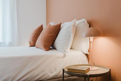 a bed with white pillows and a table with a book at Residenza al Parco in Gorizia