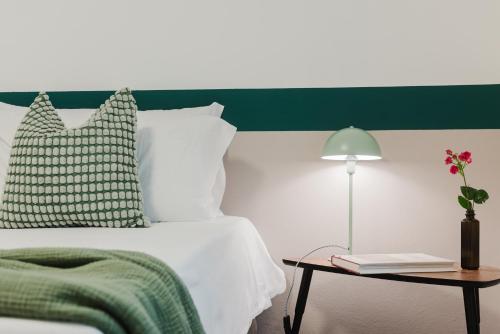 a bedroom with a white bed with a green headboard at Residenza al Parco in Gorizia