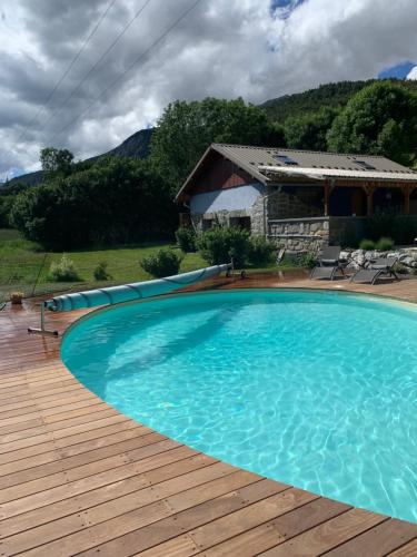 une grande piscine bleue sur une terrasse en bois dans l'établissement L'Escale en Ubaye, à Saint-Pons
