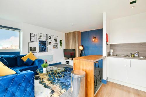 a living room with a blue couch and a kitchen at Sheffield Penthouse with Rooftop Terrace & FREE Parking in Sheffield