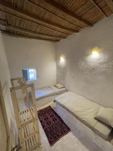 a room with two beds and a tv on the wall at Lotus House in siwa oasis