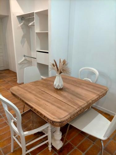 a dining room table with white chairs and a white refrigerator at Le relax max in Le Puy en Velay