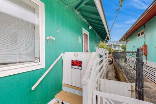 a green house with a white fence and a porch at Sea Turtle Cottage in Laie