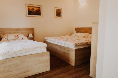 two twin beds in a bedroom with wooden floors at Penzion Fořtovna in Častrov