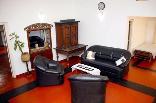 a living room with black leather furniture and a mirror at Ankelipitiya in Kotadeniyawa