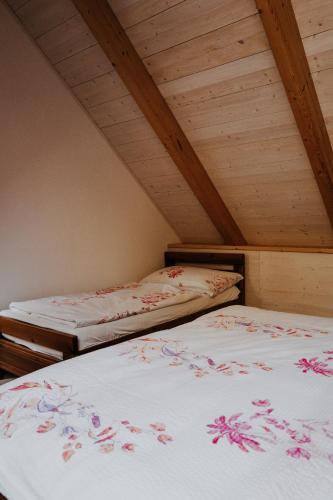 two beds in a attic room with wooden ceilings at Penzion Fořtovna in Častrov