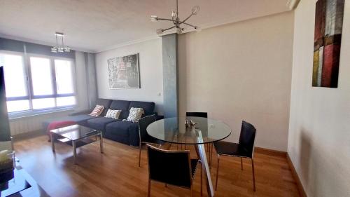 Una sala de estar con un sofá azul y una mesa de cristal. en La Casa de Sira - A 5 min de la playa a pie - Parking incluido, en Luanco