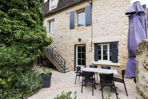 a patio with a table and chairs in front of a building at Le Trèfle à Quatre Feuilles in Siorac-en-Périgord