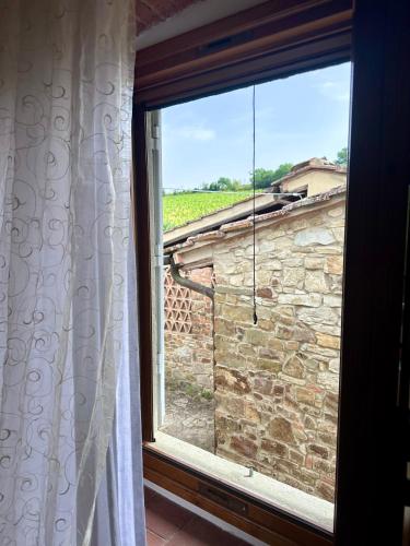 a window with a view of a stone wall at Casale Le Masse in Greve in Chianti