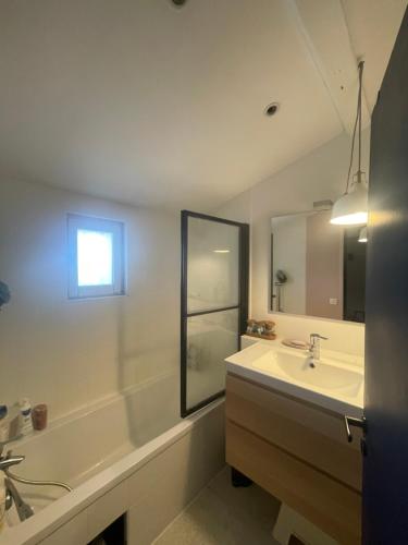 une salle de bain avec un lavabo, une baignoire et un miroir dans l'établissement Charmante maison avec piscine, à Marseille