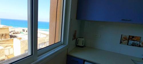 a kitchen with a window with a view of the ocean at דירה מול הים בת ים 613 in Bat Yam