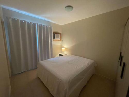 a small bedroom with a white bed and a light at Casa 3 qtos beira mar praia exclusiva e piscina in Angra dos Reis