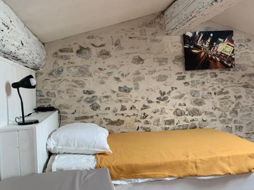 une chambre avec un lit et un mur en pierre dans l'établissement Duplex familial au cœur de la cité médiévale, à Aigues-Mortes
