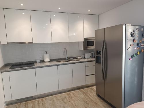 una cucina con armadi bianchi e frigorifero in acciaio inossidabile di Cachinnans Hostel & Apartments a Vila do Conde