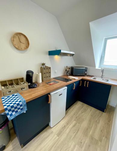 - une cuisine avec des placards bleus, un évier et une horloge dans l'établissement Le Reflet Marin - Proxi plage - Calme, au Tréport