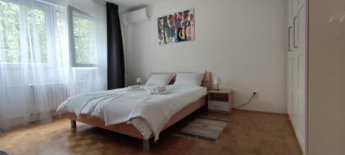a white bedroom with a bed and a window at Zg City suite in Zagreb