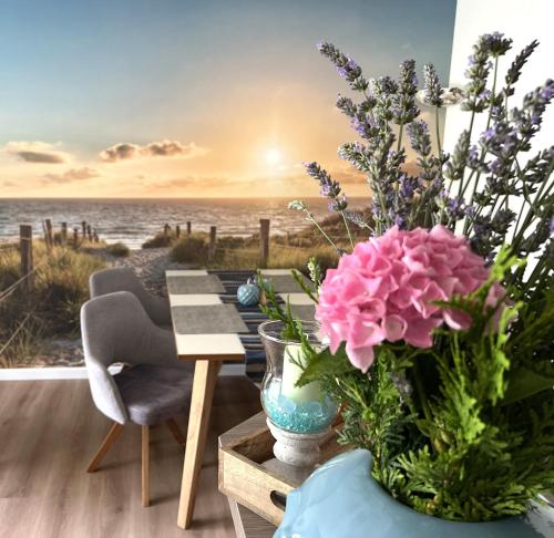 a table with a vase of flowers on a beach at Ferienwohnung Dünenhopser in Rostock