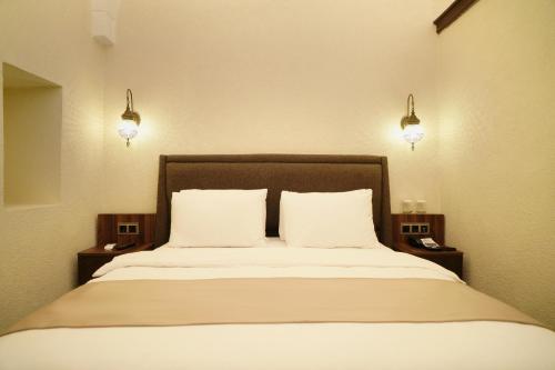 a bedroom with a bed with two pillows and two lights at Rüstempaşa Kervansaray Hotel in Edirne