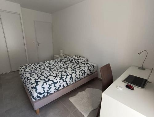 une petite chambre avec un lit et une table dans l'établissement T2 neuf avec terrasse proche Avignon, à Villeneuve-lès-Avignon