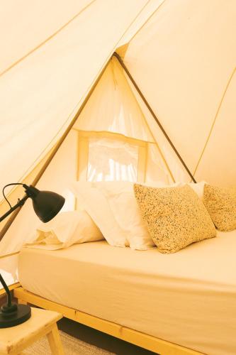 a bed in a tent with pillows on it at Tente Glamping sans vis à vis, nature & calme, côte Vicentine in Rogil