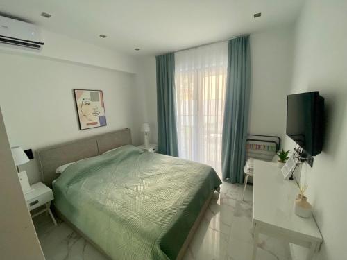 a bedroom with a bed and a flat screen tv at AquaLux Apartment in Kallithea Halkidikis