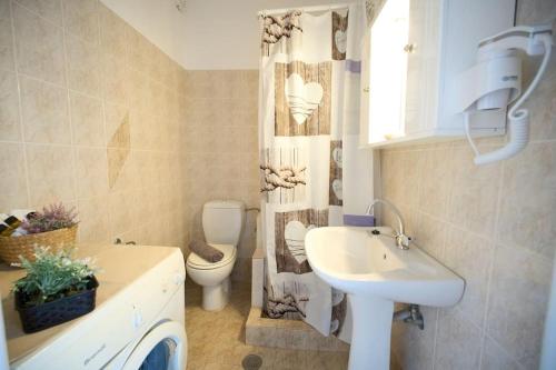 a bathroom with a sink and a toilet and a shower curtain at Blue Dreams Astros in Paralio Astros