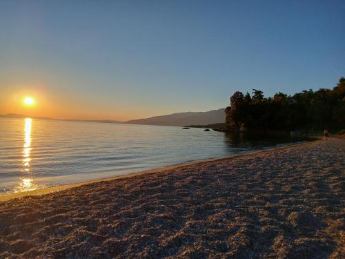 a beach with the sun setting over the water at Margianou Seaview Apartments 3 & 4 in Kálamos