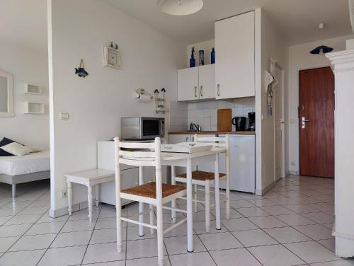 une cuisine avec des armoires blanches et une table et des chaises dans l'établissement Côté Océan, Vue Mer et Terrasse, à La Rochelle