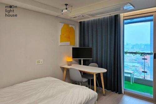 a bedroom with a desk and a bed and a window at Moonlight Sokcho - High-rise, Ocean and City View in Sokcho