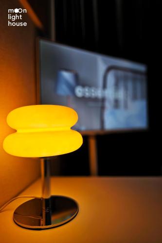 a yellow lamp sitting on a table in front of a tv at Moonlight Sokcho - High-rise, Ocean and City View in Sokcho