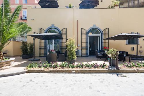 a patio with tables and umbrellas and flowers at Domus Xenia in San Giorgio a Cremano