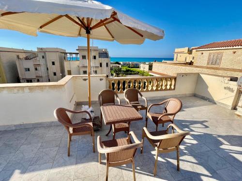 a patio with a table and chairs and an umbrella at Sea & Pool View Deluxe Chalet - Prime Spot in Badr Resort in El Alamein