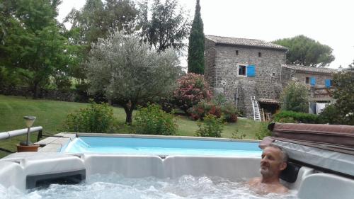 un homme dans un bain à remous dans une cour dans l'établissement Nid douillet en Ardèche, à Chomérac